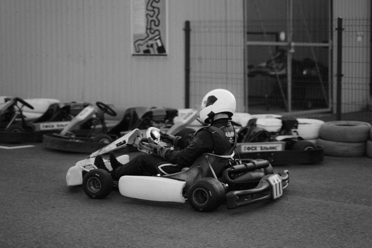 Black and white photo of a go-kart driver in action on a track.