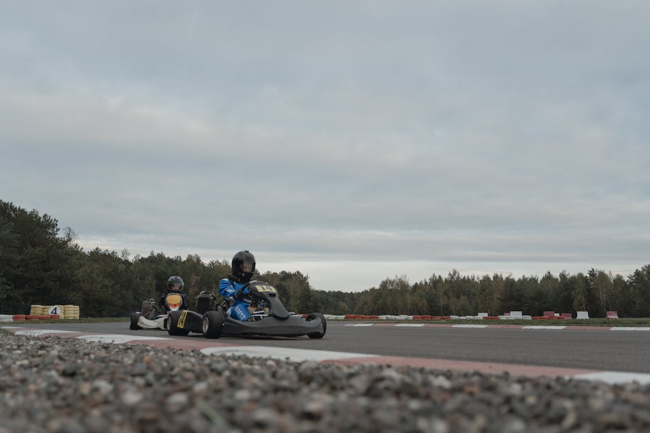 Intense outdoor go-kart racing competition on a cloudy day. Athletes navigate the racetrack with precision.
