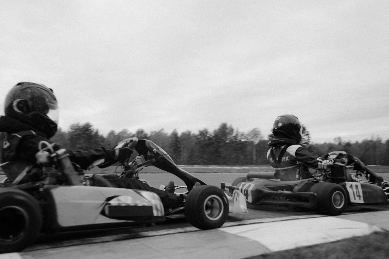 Close-up of racers competing in a high-speed go-kart race on an outdoor track.