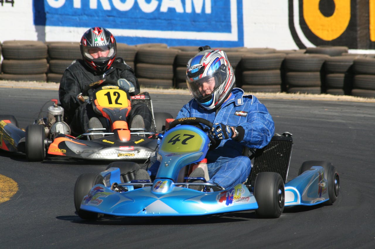 Competitive go-kart racing with drivers in helmets and racing suits on track.