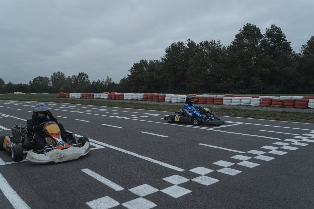 Two racers compete at the starting line on a go-kart race track.