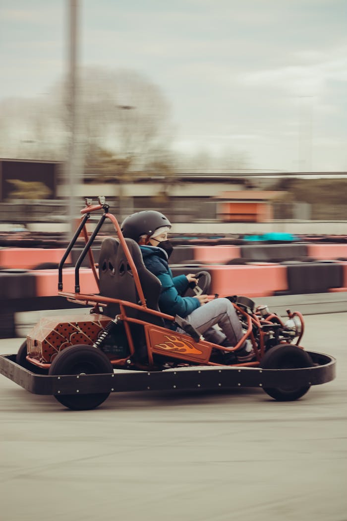 our-mission A teenager in a helmet driving a go-kart on an outdoor speedway, capturing the thrill and motion.