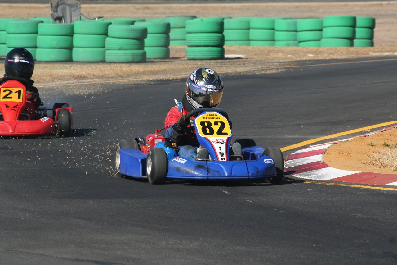 Thrilling go-kart race action on a sunny outdoor track with drivers in helmets and numbered karts.